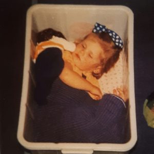 Flicka sover på golvet i en låda.